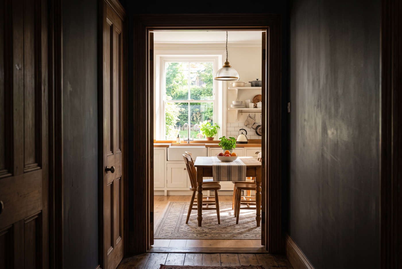 View through a dark doorway into a bright sunlit kitchen
